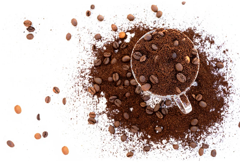 Kaffeetasse mit gemahlenem Kaffe und Bohnen